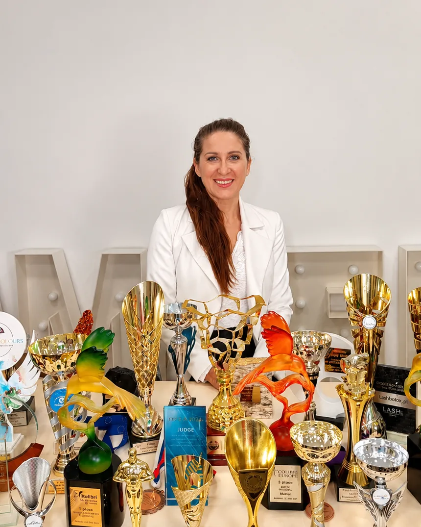 Grażyna Kleba, founder of GK Academy, beside trophies won at beauty industry championships